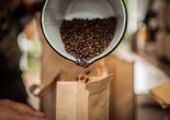 Alameda resident and a warehouse manager-in-training Celeste Freeman, 47, pours roasted coffee beans into bags to be weighed at Red Bay Coffee's roasting lab in Oakland. (Photo by Ekevara Kitpowsong/ Bay News Rising)
