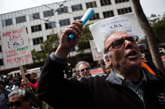 Protesters assemble picket signs slamming Uber business practices outside company headquarters on Market Street June 22. (Photo by Khaled Sayed/Bay News Rising)