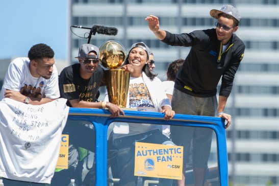 Warriors MVP Steph Curry waves to fans while teammate Andre Iguodala holds the championship trophy. (Photo by Khaled Sayed/Bay News Rising)