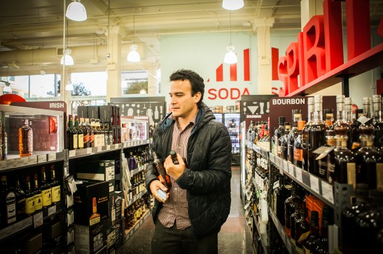 Homero Hidalgo, 35, works part time as postmates courier, buying liquors for customer who requested delivery order through the Postmates app, at BevMo! store on Van Ness Avenue, Friday, July 17, 2015. (Photo by Ekevara Kitpowsong/Bay News Rising)