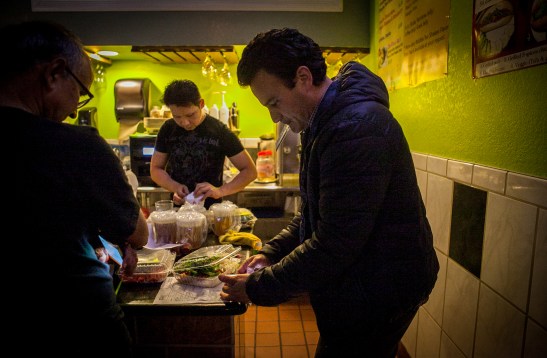 A part time postmates courier Homero Hidalgo, 35, pays for the order of food which the customer requested delivery through the Postmates app at Miss Saigon Vietnamese Cuisine on Friday, July 17, 2015. (Photo by Ekevara Kitpowsong/Bay News Rising)