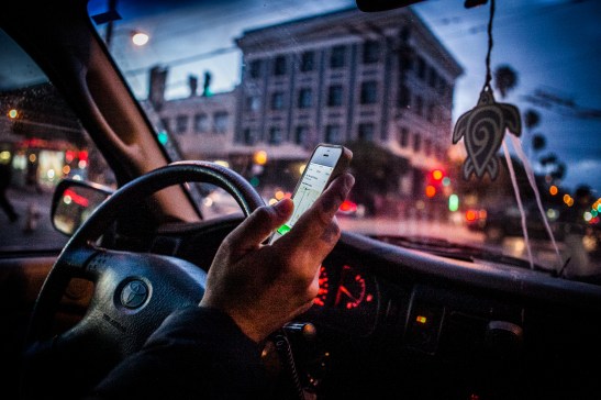A part time postmates courier Homero Hidalgo, 35, checks for next delivery requests through a Postmates app on his cell phone after completed his recent delivery task, Friday, July 17, 2015. (Photo by Ekevara Kitpowsong/Bay News Rising)