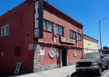 The exterior of a two-story building, which has a sign that reads "topless girls"