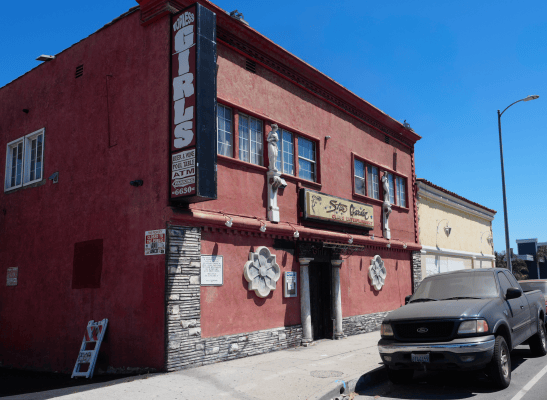 The exterior of a two-story building, which has a sign that reads "topless girls"